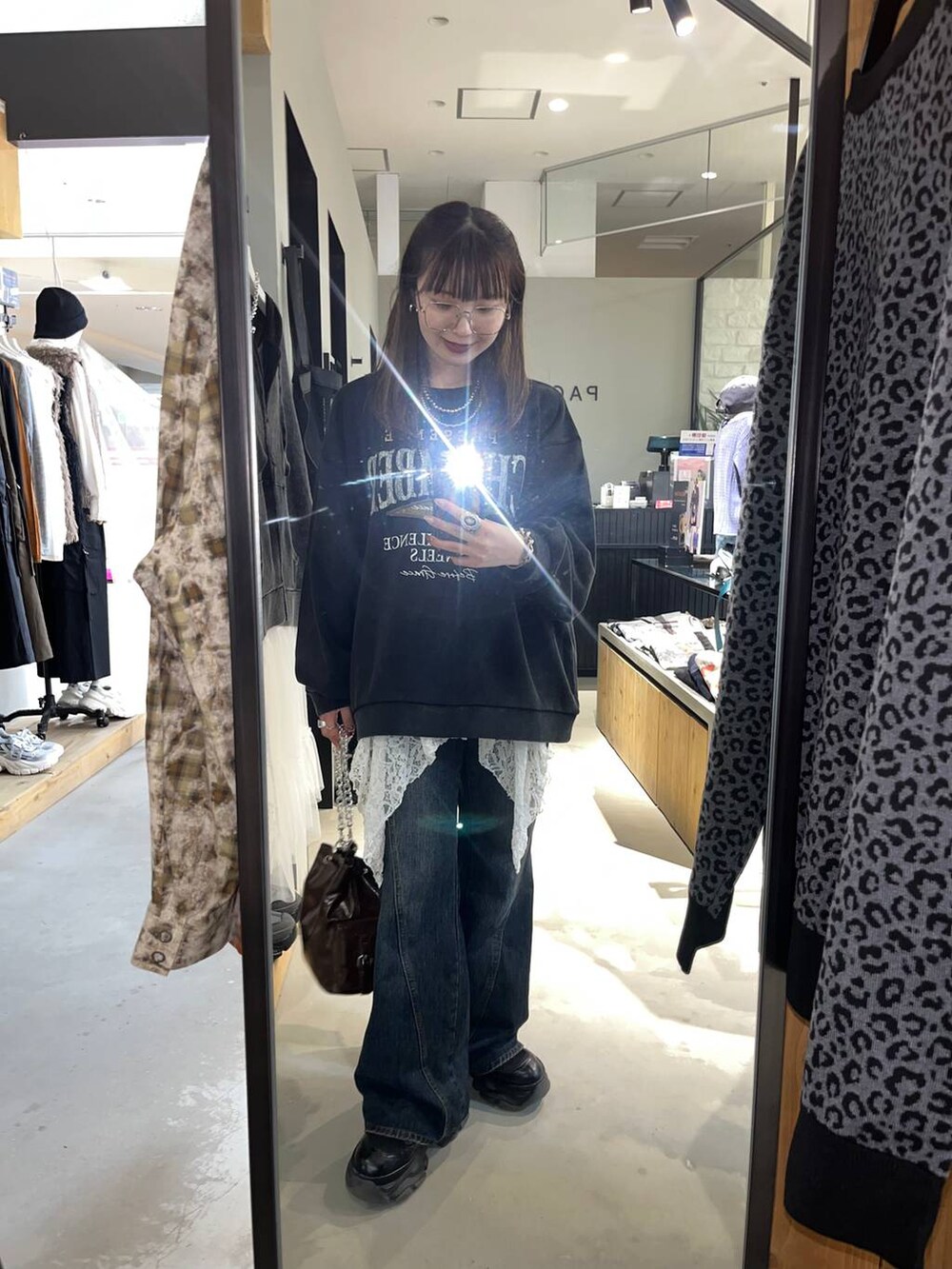 ブラック系のブーツ、ブルー系のデニムパンツ、ブラウン系のショルダーバッグを着用したレディースの秋コーディネートの2枚目の写真