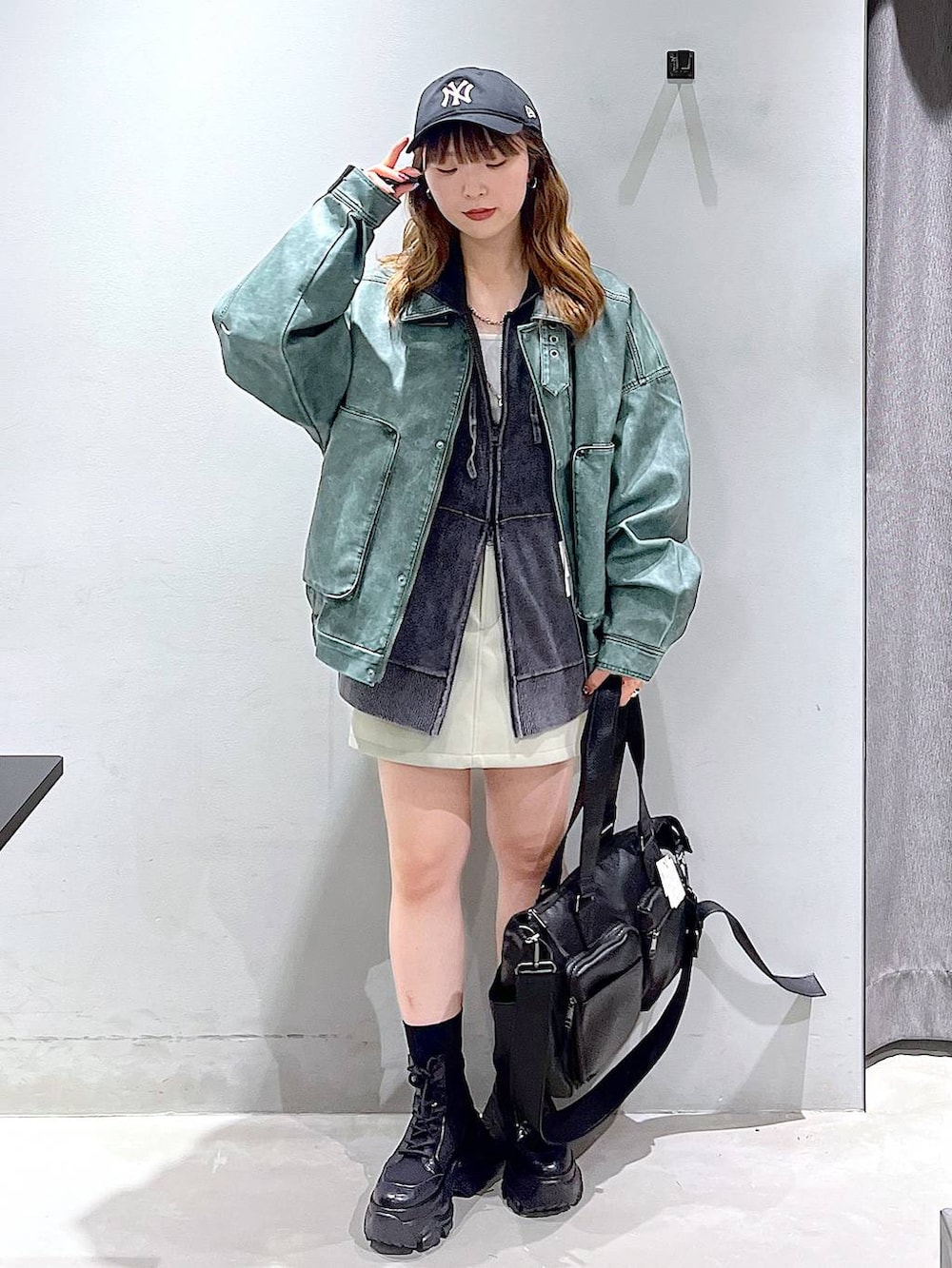 ブラック系のブーツ、ブラック系のボストンバッグ、グレー系のパーカーを着用したレディースの秋コーディネートの2枚目の写真