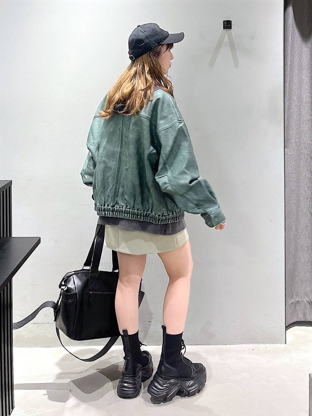 ブラック系のブーツ、ブラック系のボストンバッグ、グレー系のパーカーを着用したレディースの秋コーディネートの4枚目の写真