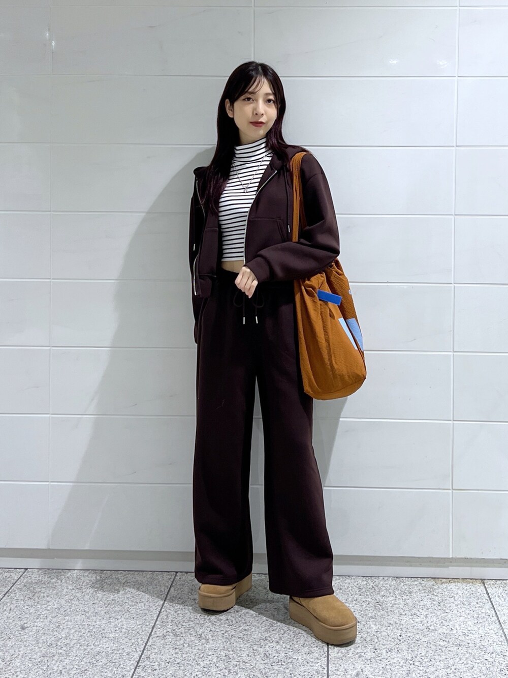 ホワイト系のTシャツ/カットソー、ブラウン系のトートバッグ、ブラウン系のブーツを着用したレディースの秋コーディネートの4枚目の写真