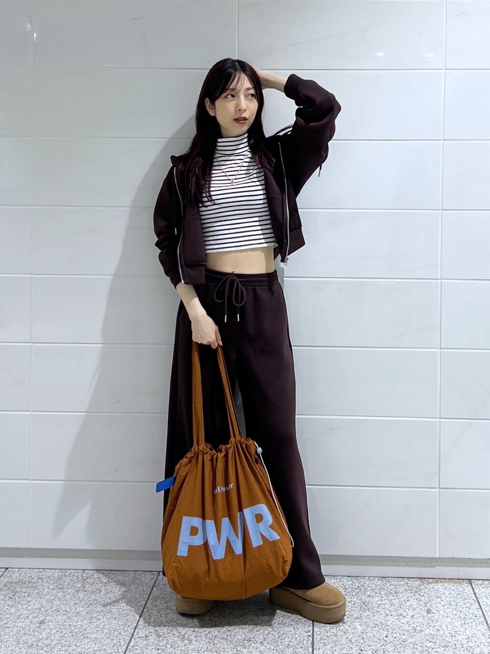 ホワイト系のTシャツ/カットソー、ブラウン系のトートバッグ、ブラウン系のブーツを着用したレディースの秋コーディネートの2枚目の写真