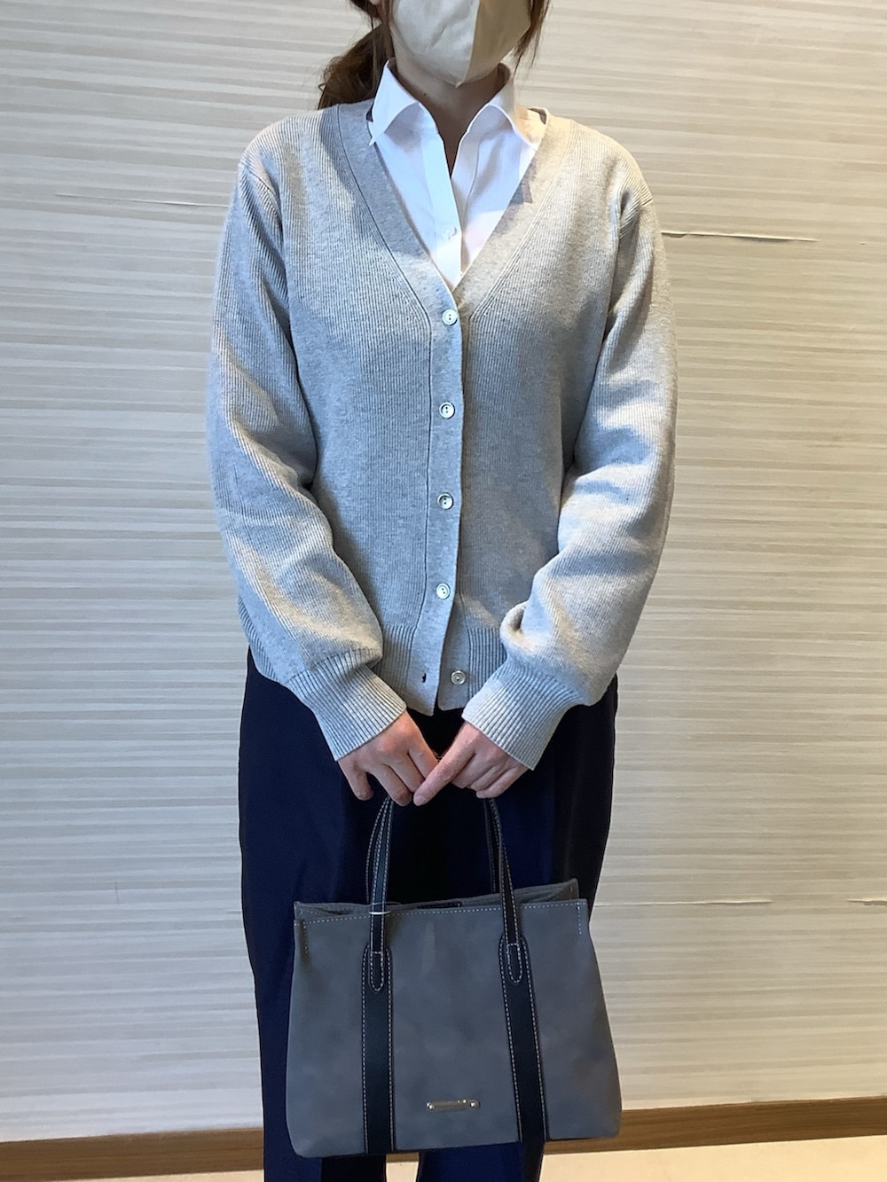 ホワイト系のビジネスシャツ、グレー系のカーディガン/ボレロ、ブルー系のスラックスを着用したレディースの冬コーディネートの2枚目の写真