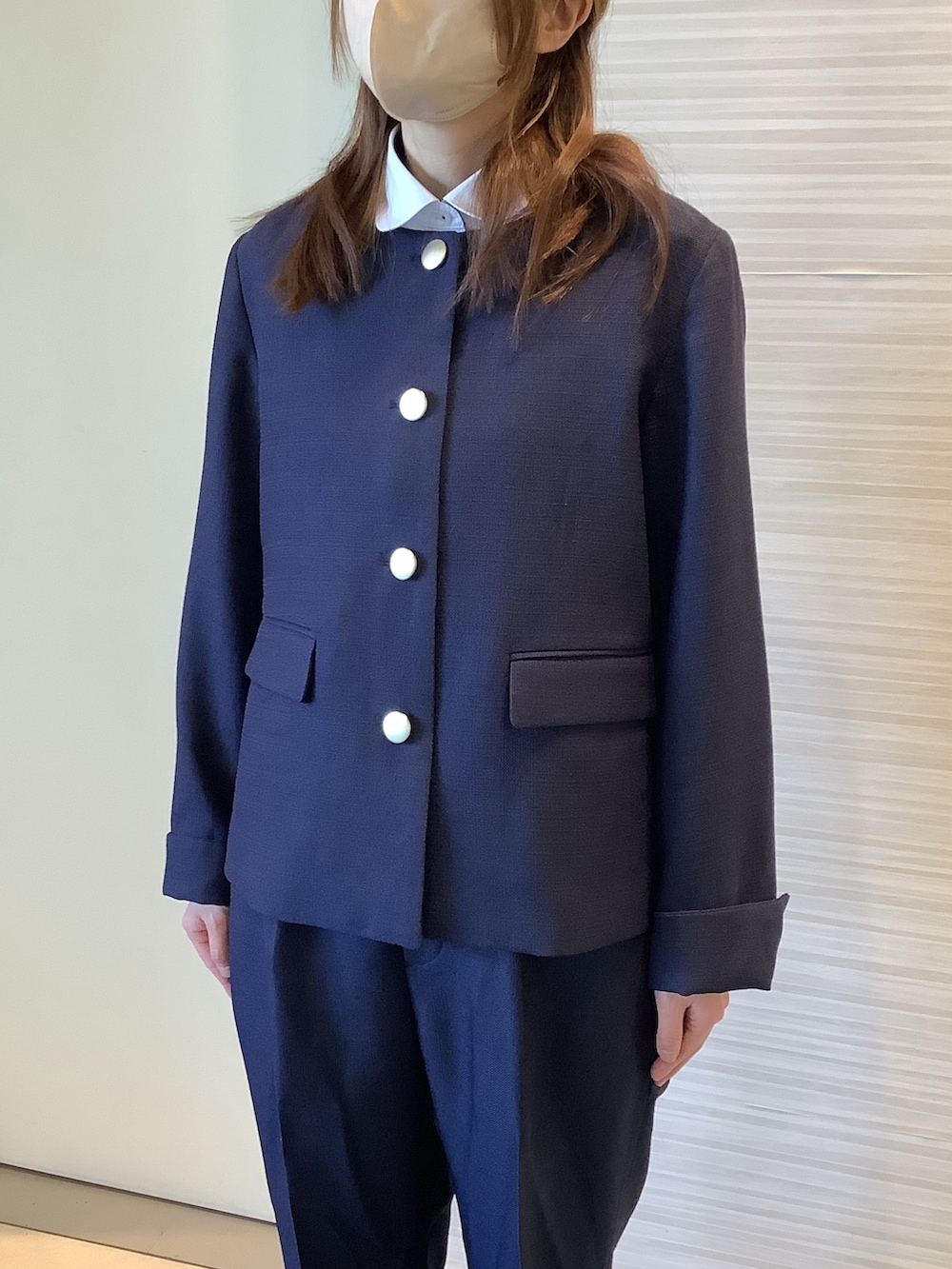 ブルー系のスラックス、ブルー系のノーカラーコート、ホワイト系のビジネスシャツを着用したレディースの冬コーディネートの2枚目の写真