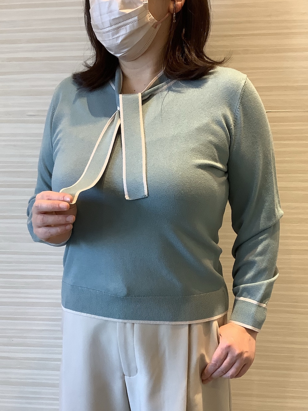 グリーン系のニット/セーターを着用したレディースの春コーディネートの2枚目の写真