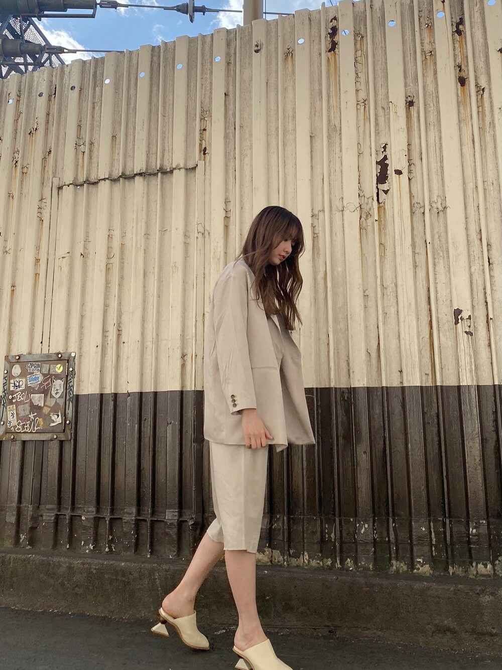 グレー系のテーラードジャケット、ホワイト系のサンダル、ブラック系のTシャツ/カットソーを着用したレディースの冬コーディネートの3枚目の写真