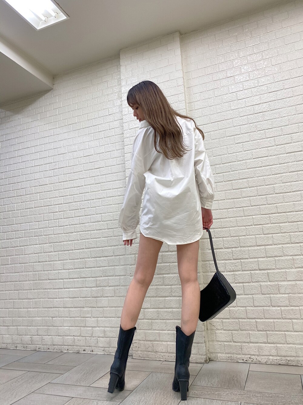 ベージュ系のデニムスカート、ブラック系のブーツ、ホワイト系のシャツ/ブラウスを着用したレディースの冬コーディネートの3枚目の写真