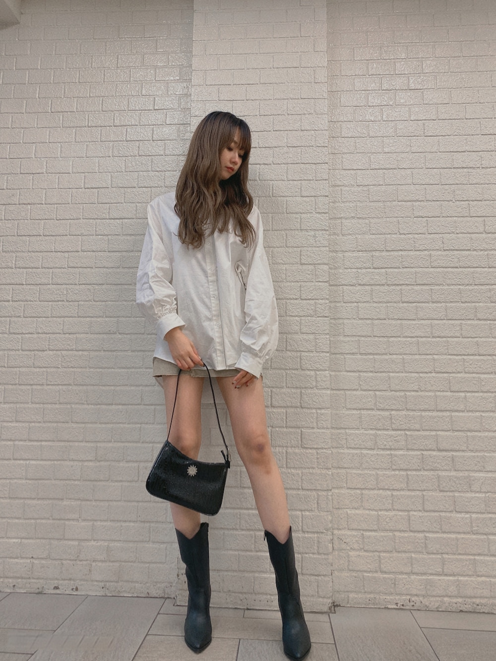 ベージュ系のデニムスカート、ブラック系のブーツ、ホワイト系のシャツ/ブラウスを着用したレディースの冬コーディネートの2枚目の写真