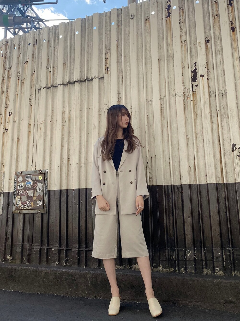 グレー系のテーラードジャケット、ホワイト系のサンダル、ブラック系のTシャツ/カットソーを着用したレディースの冬コーディネートの2枚目の写真