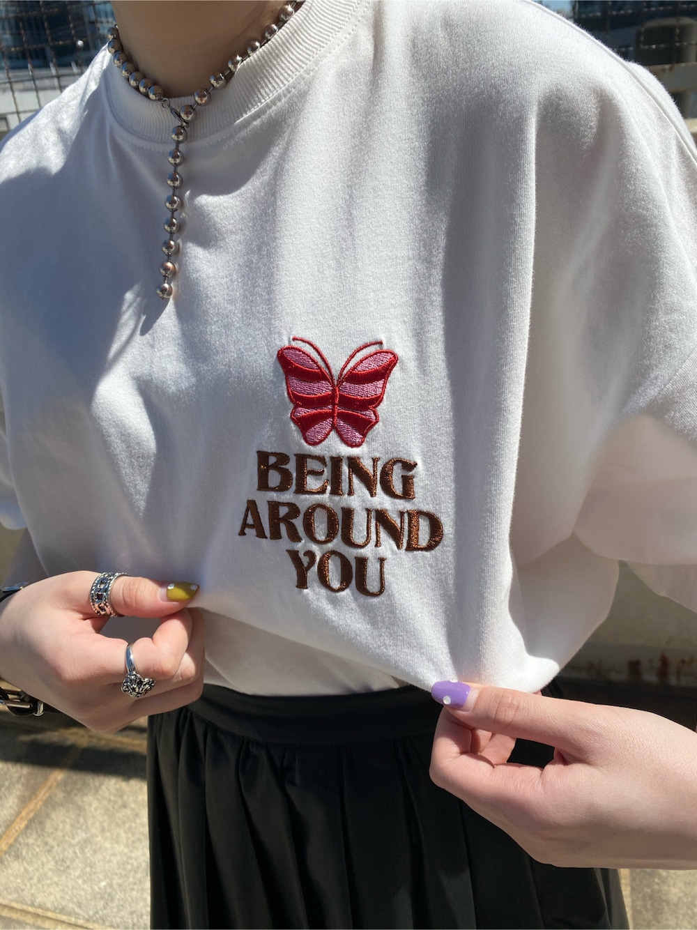 ブラック系のスカート、ホワイト系のTシャツ/カットソーを着用したレディースの春コーディネートの6枚目の写真