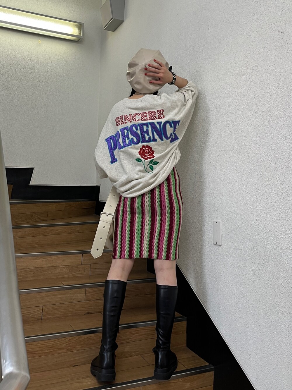 レッド系のスカート、グレー系のTシャツ/カットソー、ブラック系のブーツを着用したレディースの秋コーディネートの2枚目の写真