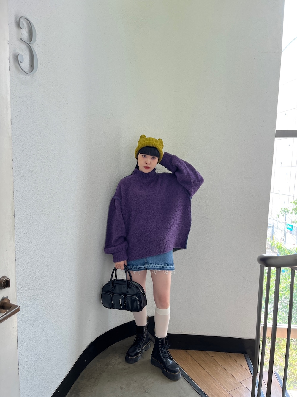 パープル系のニット/セーター、ブルー系のデニムパンツ、グリーン系のボストンバッグを着用したレディースの秋コーディネートの2枚目の写真