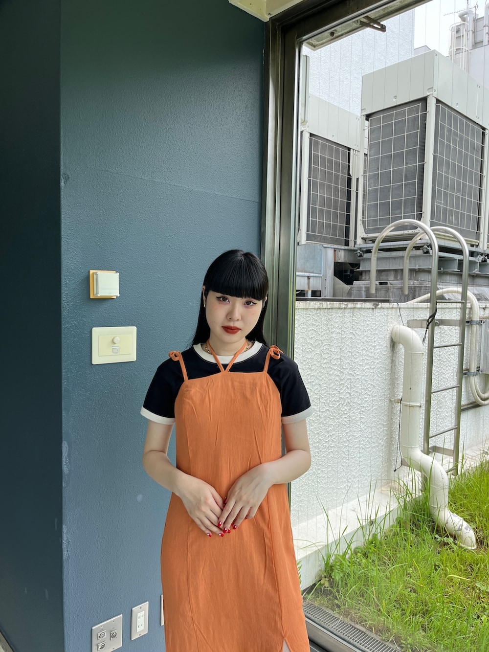 オレンジ系のワンピース、ホワイト系のTシャツ/カットソー、ブラック系のブーツを着用したレディースの夏コーディネートの4枚目の写真