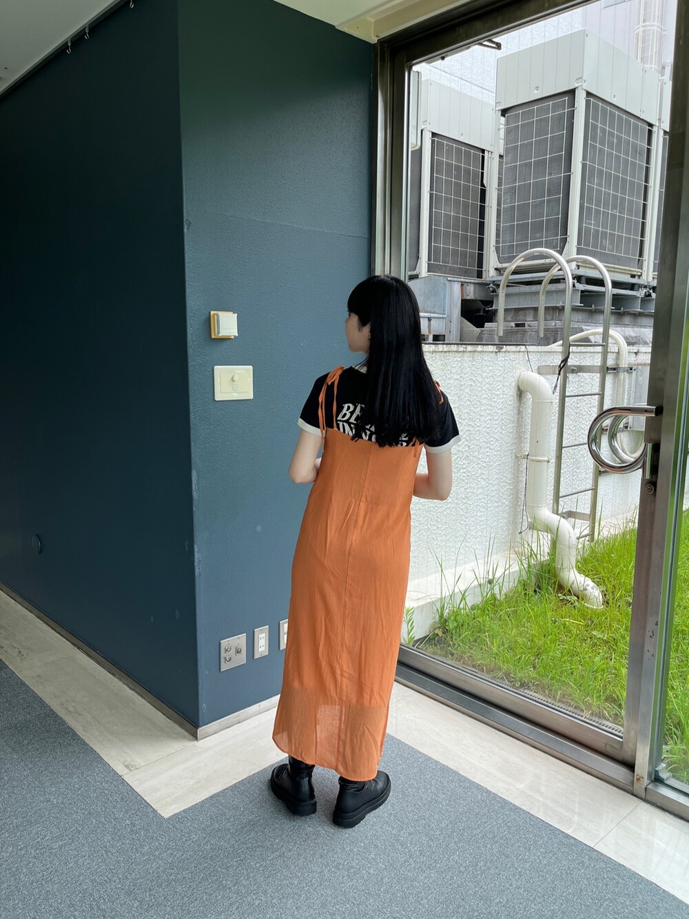 オレンジ系のワンピース、ホワイト系のTシャツ/カットソー、ブラック系のブーツを着用したレディースの夏コーディネートの3枚目の写真