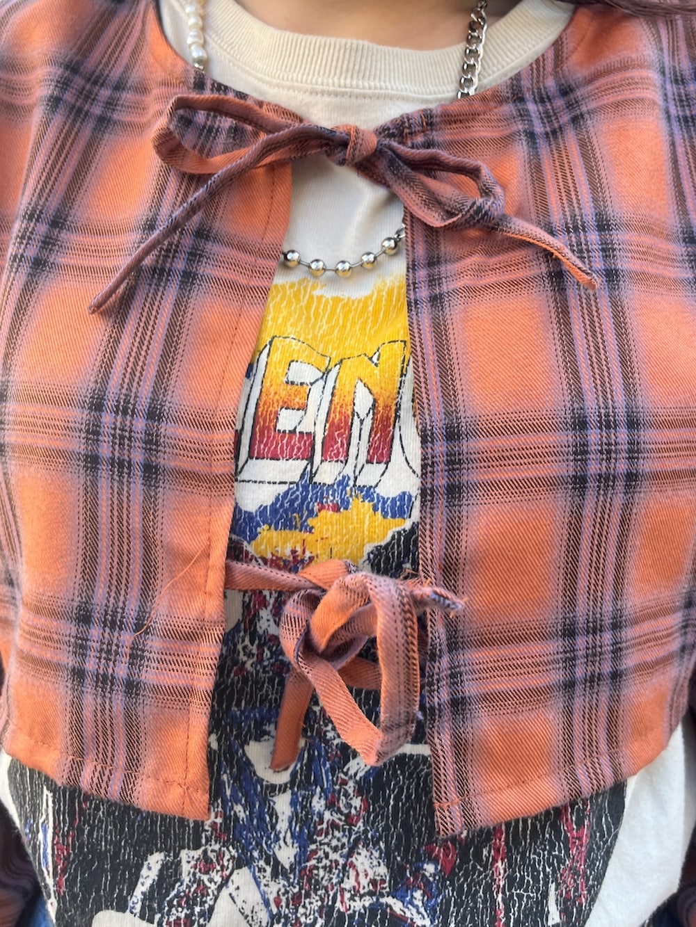 オレンジ系のワンピース、ブラック系のブーツ、ブルー系のデニムパンツを着用したレディースの冬コーディネートの6枚目の写真