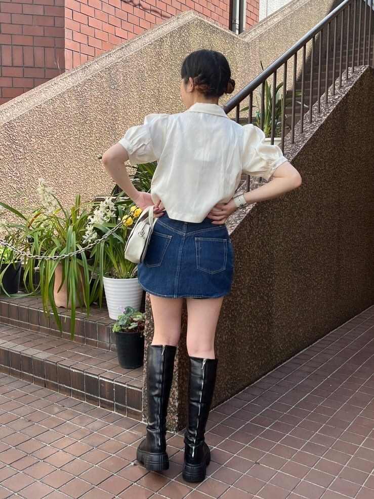 ホワイト系のボストンバッグ、ブラック系のブーツ、ブルー系のデニムスカートを着用したレディースの夏コーディネートの3枚目の写真