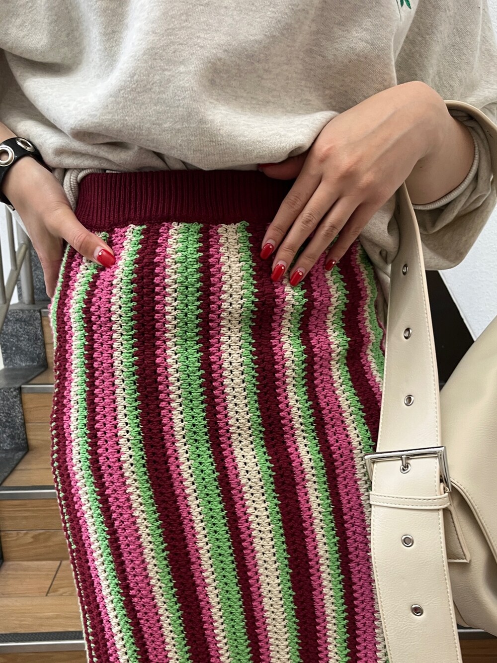 レッド系のスカート、グレー系のTシャツ/カットソー、ブラック系のブーツを着用したレディースの秋コーディネートの6枚目の写真