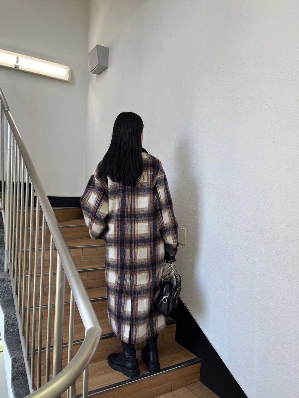 ブラック系のブーツ、ブラック系のハンドバッグ、ホワイト系のチェスターコートを着用したレディースの夏コーディネートの3枚目の写真