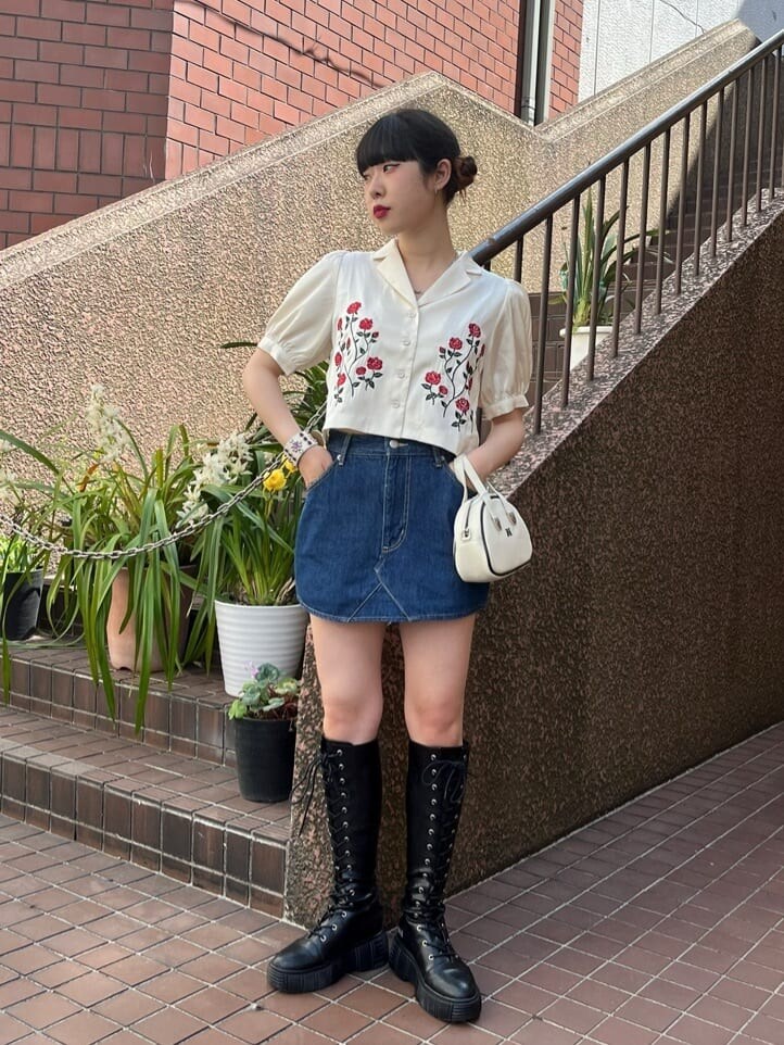 ホワイト系のボストンバッグ、ブラック系のブーツ、ブルー系のデニムスカートを着用したレディースの夏コーディネートの2枚目の写真