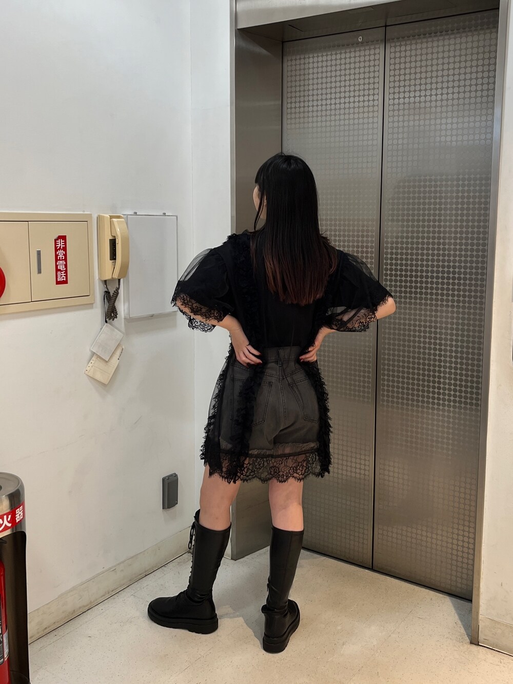 ブラック系のワンピース、ブラック系のブーツ、ブラック系のデニムパンツを着用したレディースの春コーディネートの3枚目の写真