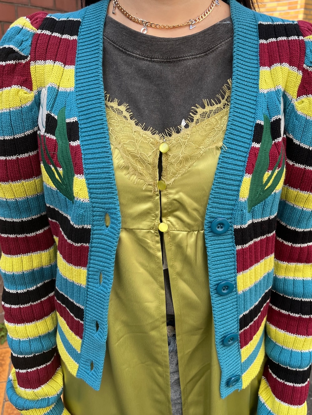 グリーン系のワンピース、ブラック系のブーツ、ブルー系のデニムパンツを着用したレディースの春コーディネートの7枚目の写真