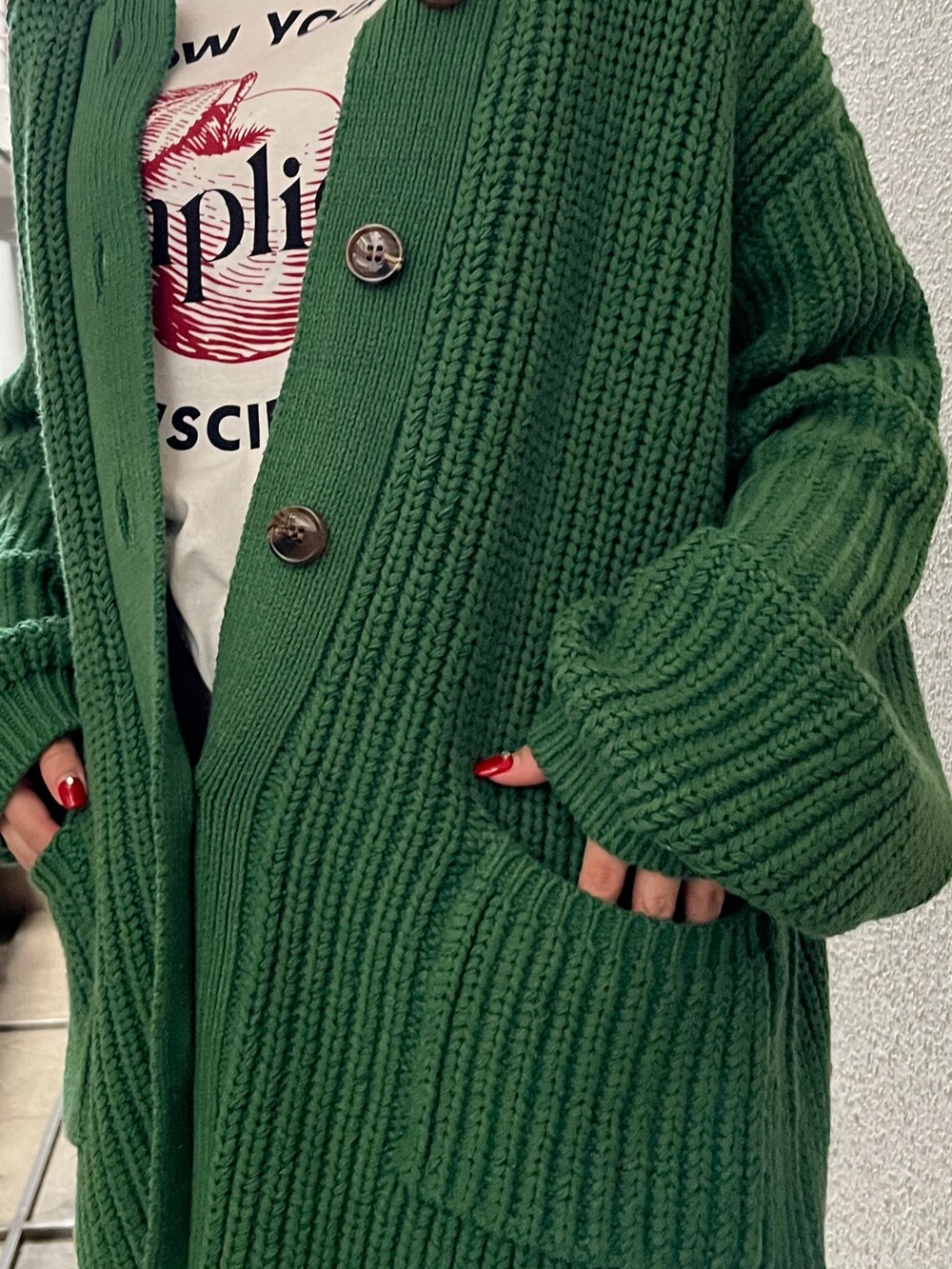 グリーン系のカーディガン/ボレロ、ホワイト系のTシャツ/カットソーを着用したレディースの秋コーディネートの6枚目の写真