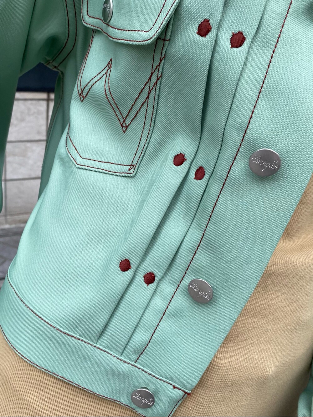 グリーン系のデニムジャケット、ベージュ系のチュニックを着用したレディースの春コーディネートの5枚目の写真