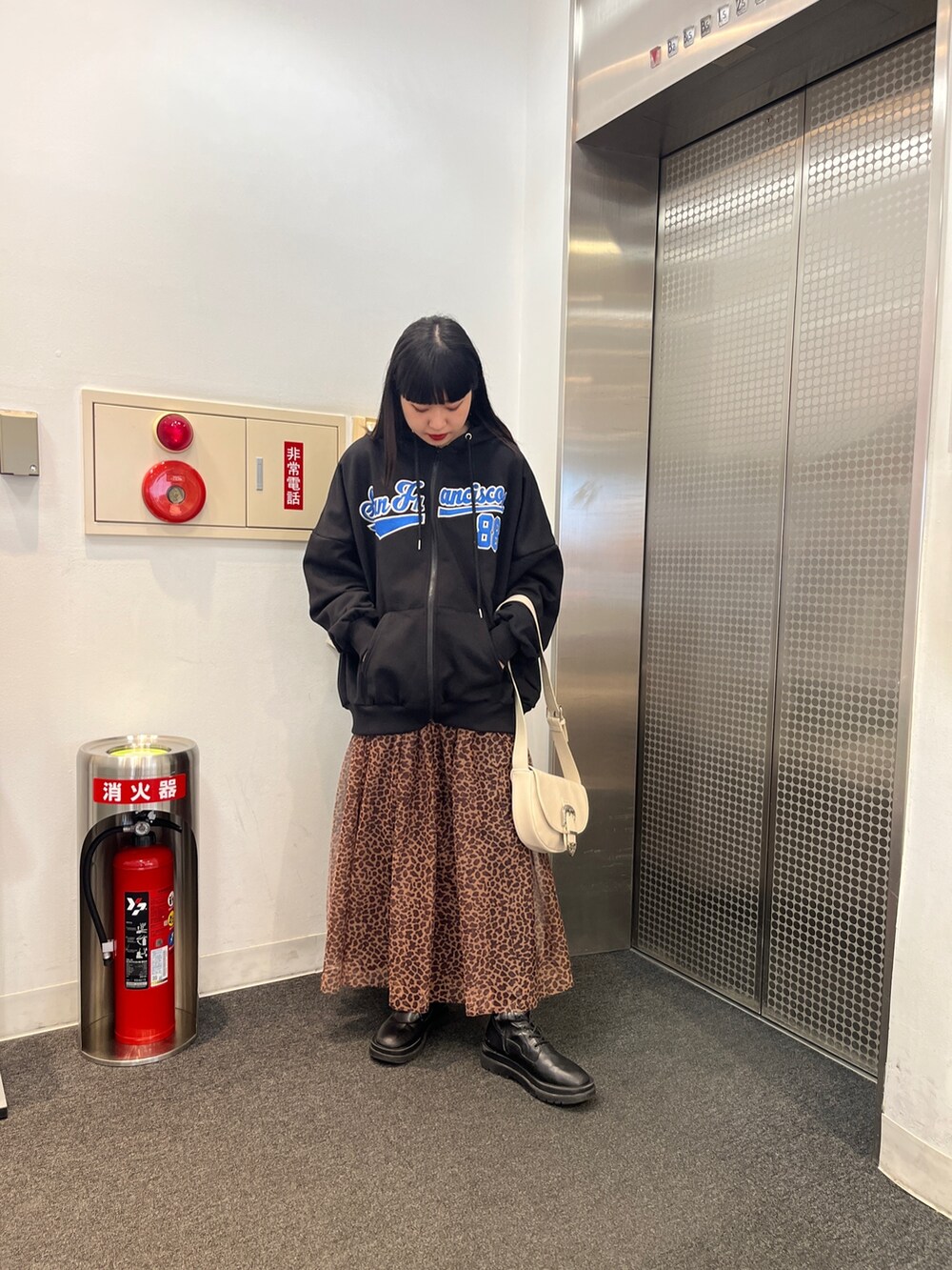 その他のスカート、ブラック系のパーカー、ホワイト系のショルダーバッグを着用したレディースの冬コーディネートの2枚目の写真