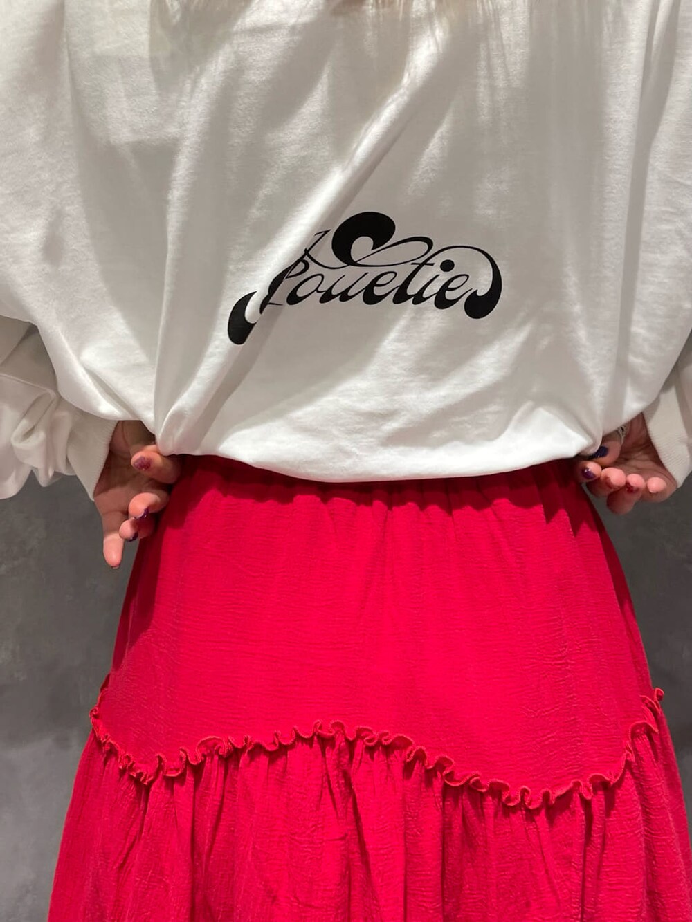 レッド系のスカート、ホワイト系のブーツ、ホワイト系のTシャツ/カットソーを着用したレディースの夏コーディネートの4枚目の写真