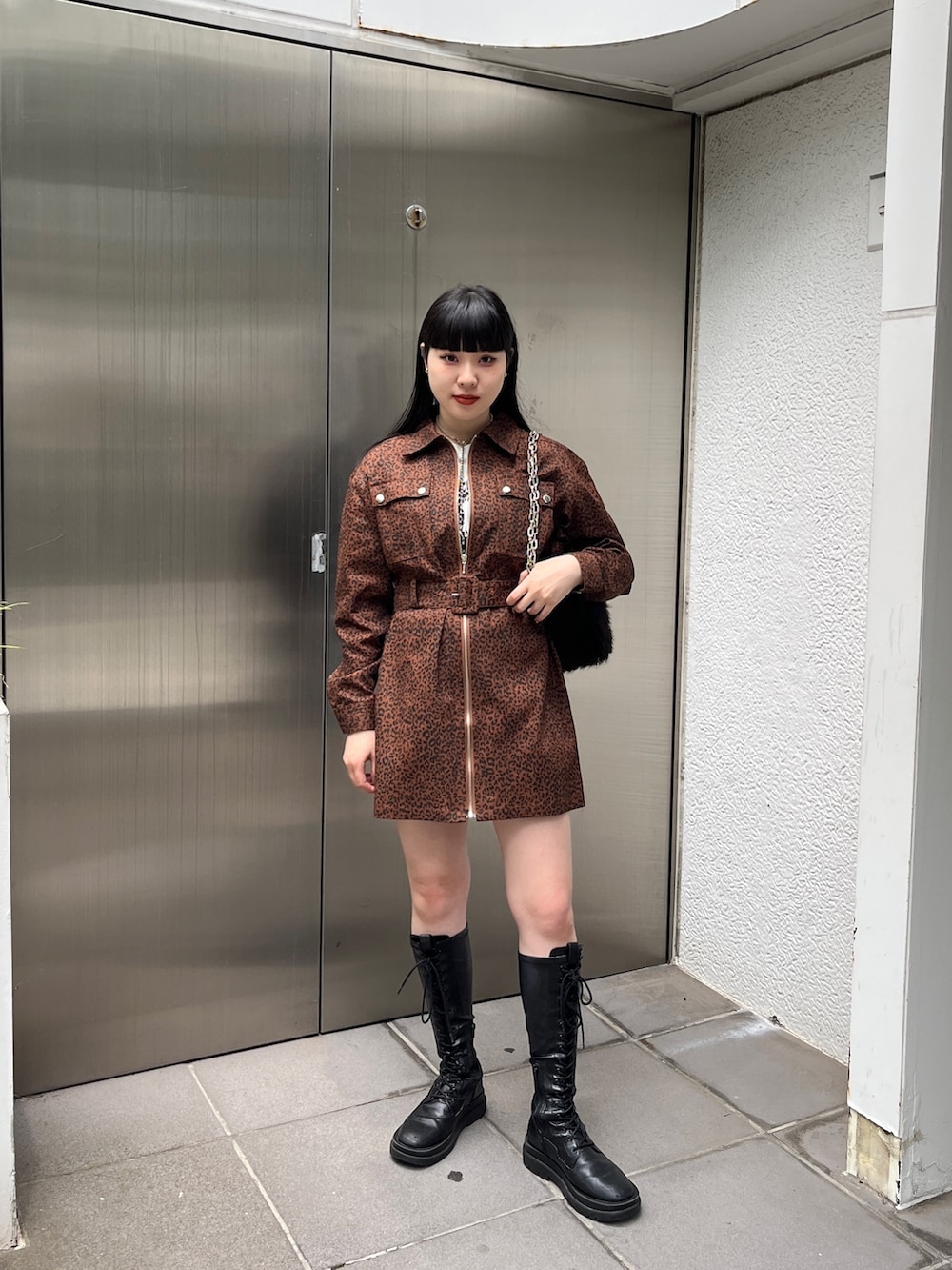 ブラック系のブーツ、ブラウン系のワンピース、ブラック系のハンドバッグを着用したレディースの夏コーディネートの2枚目の写真