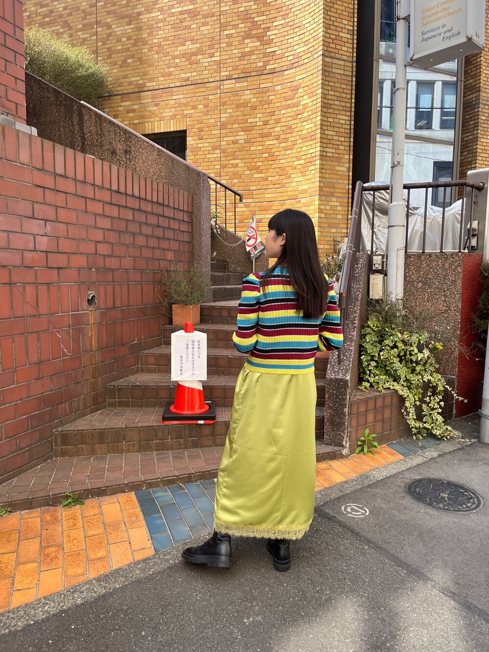 グリーン系のワンピース、ブラック系のブーツ、ブルー系のデニムパンツを着用したレディースの春コーディネートの3枚目の写真