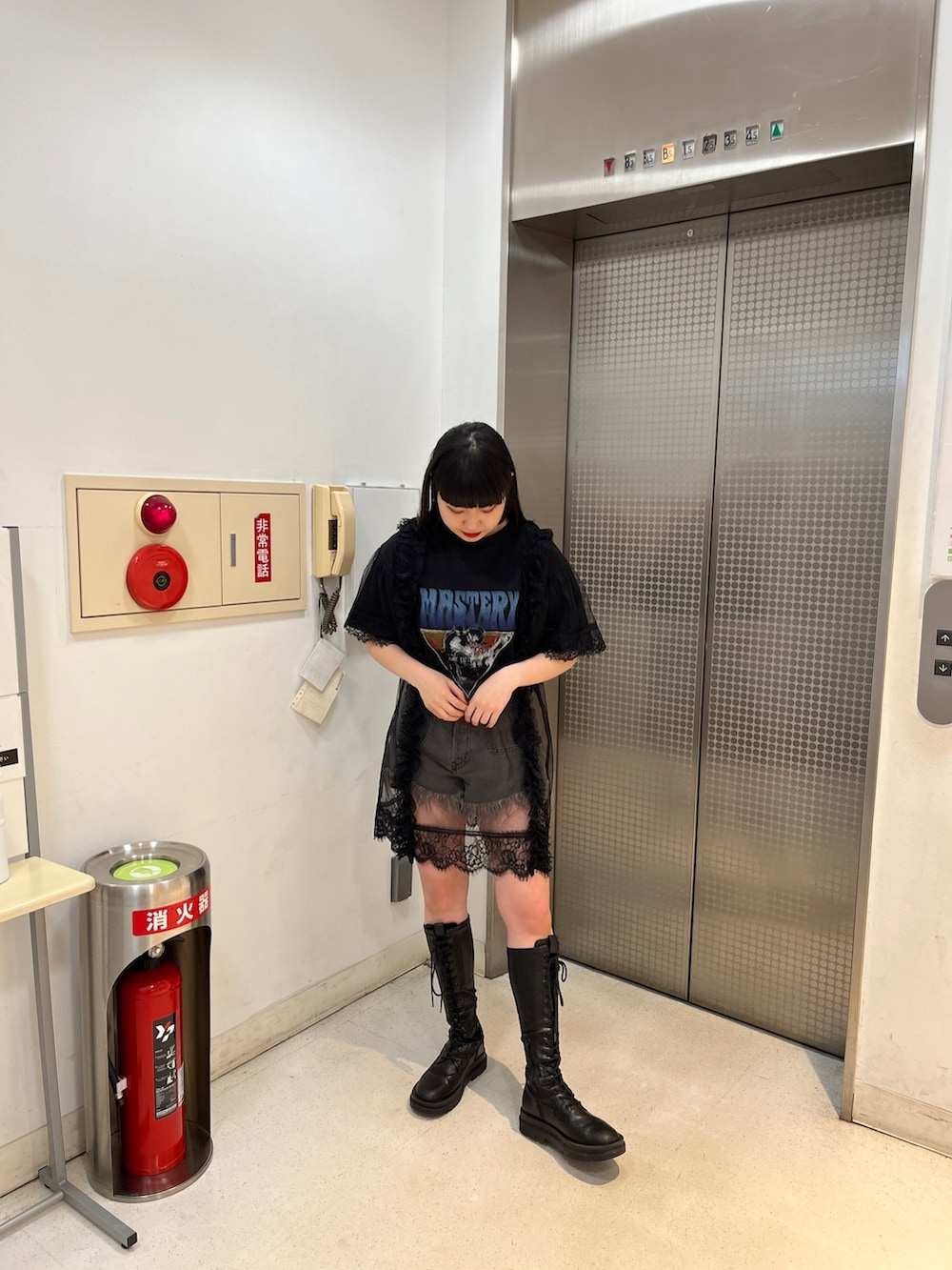 ブラック系のワンピース、ブラック系のブーツ、ブラック系のデニムパンツを着用したレディースの春コーディネートの2枚目の写真