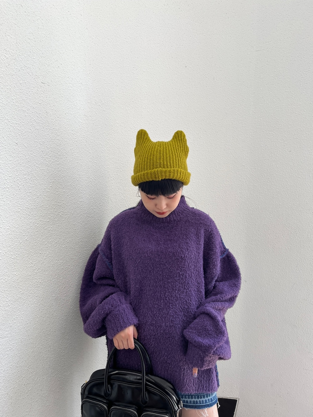 パープル系のニット/セーター、ブルー系のデニムパンツ、グリーン系のボストンバッグを着用したレディースの秋コーディネートの5枚目の写真