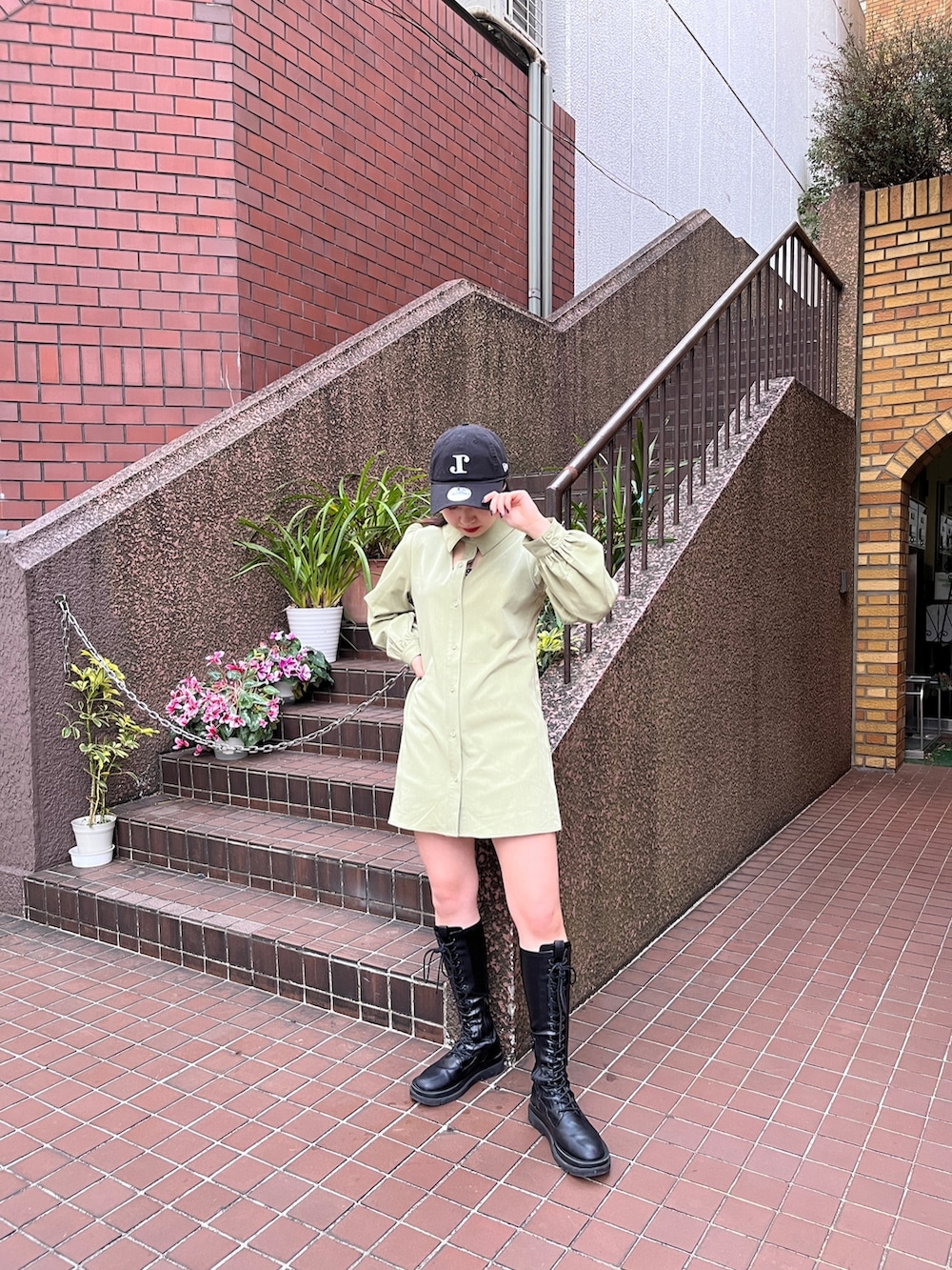 グリーン系のワンピース、ブラック系のブーツ、ブラック系のキャップを着用したレディースの冬コーディネートの3枚目の写真