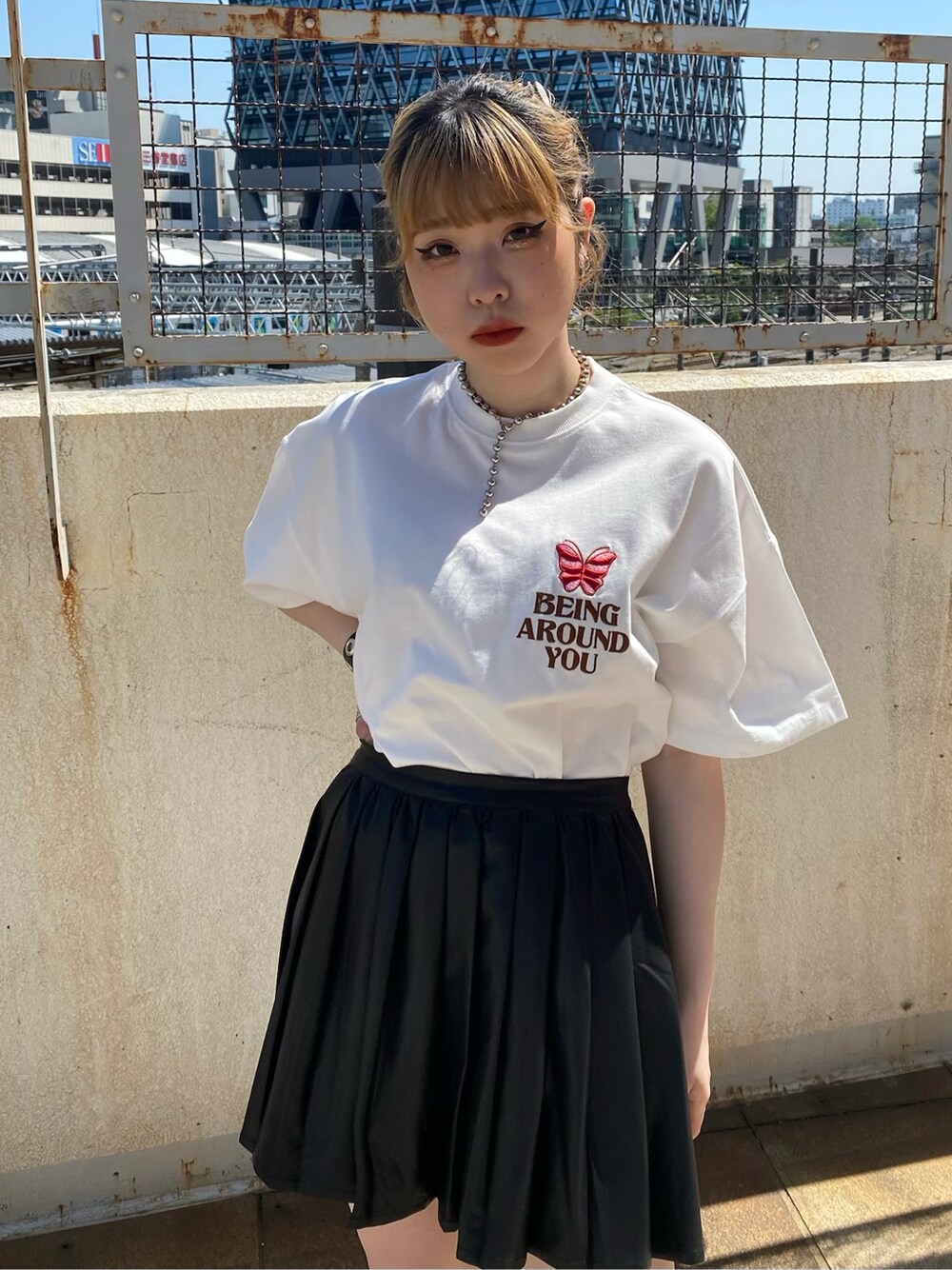 ブラック系のスカート、ホワイト系のTシャツ/カットソーを着用したレディースの春コーディネートの4枚目の写真