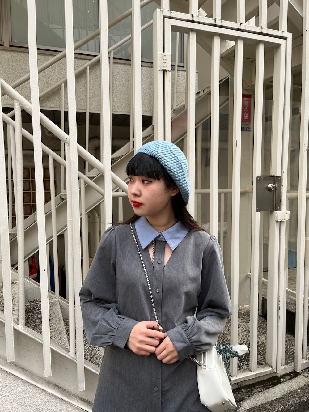 グレー系のワンピース、ブラック系のブーツ、ホワイト系のショルダーバッグを着用したレディースの冬コーディネートの5枚目の写真