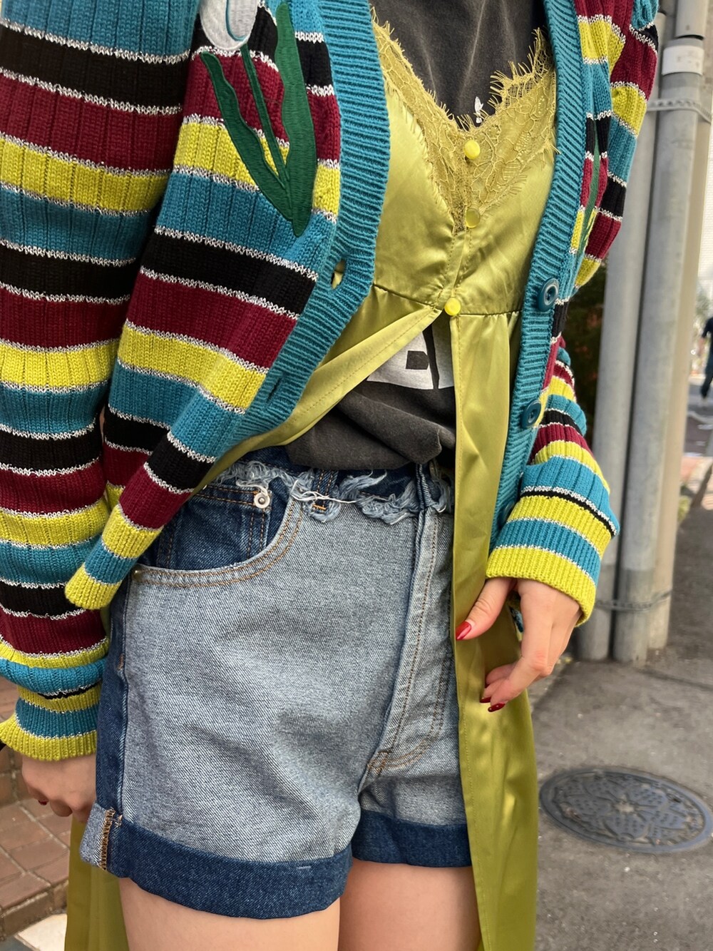 グリーン系のワンピース、ブラック系のブーツ、ブルー系のデニムパンツを着用したレディースの春コーディネートの9枚目の写真