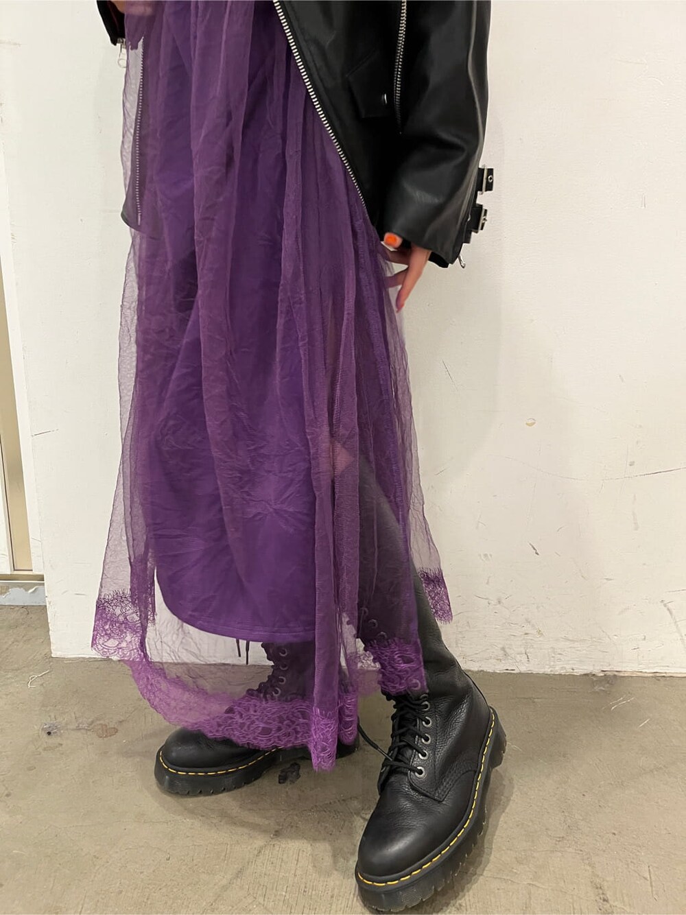 ブラック系のライダースジャケット、パープル系のワンピースを着用したレディースの秋コーディネートの6枚目の写真