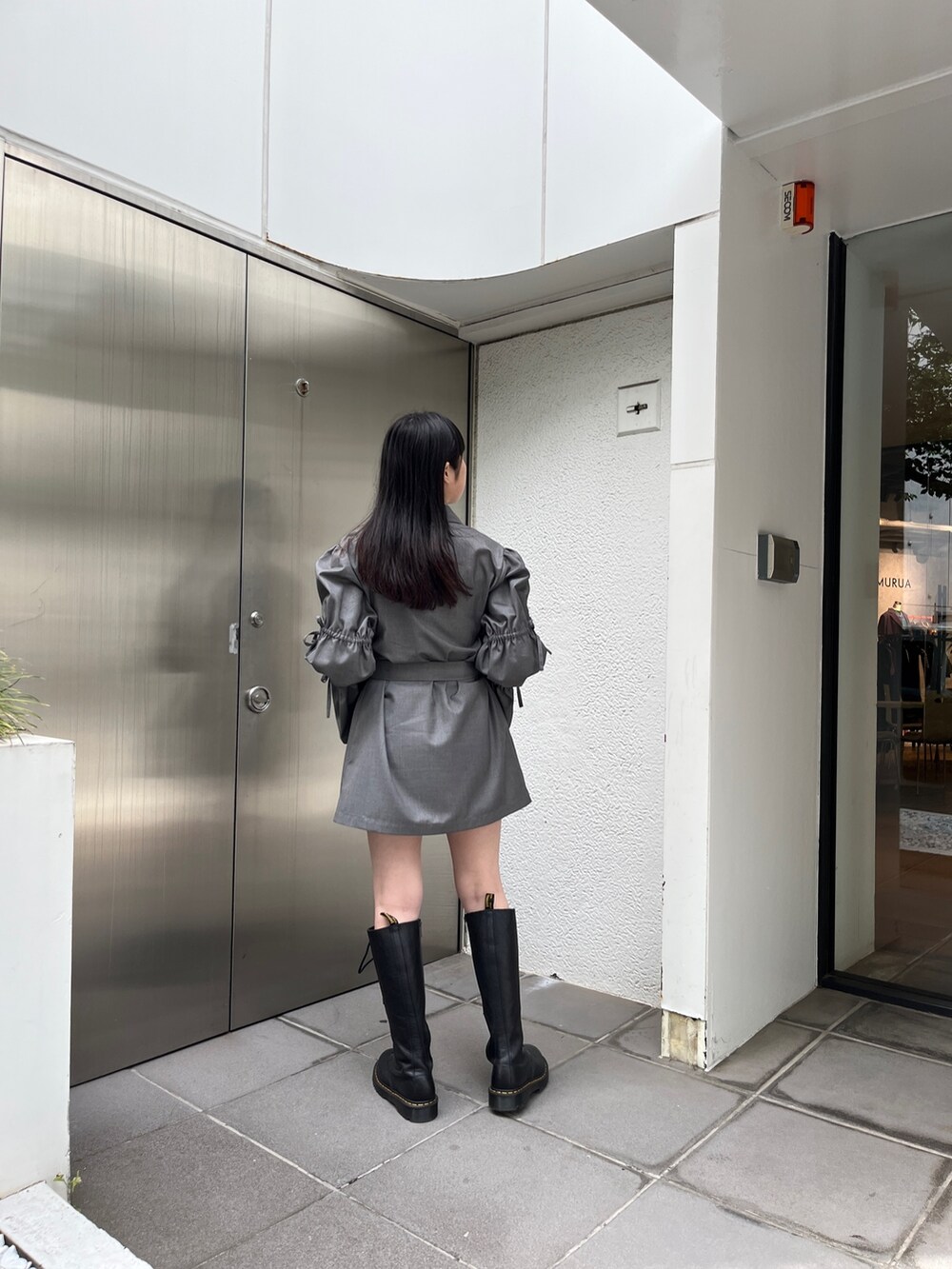 グレー系のワンピース、ブラック系のブーツ、シルバー系のネックレスを着用したレディースの夏コーディネートの4枚目の写真