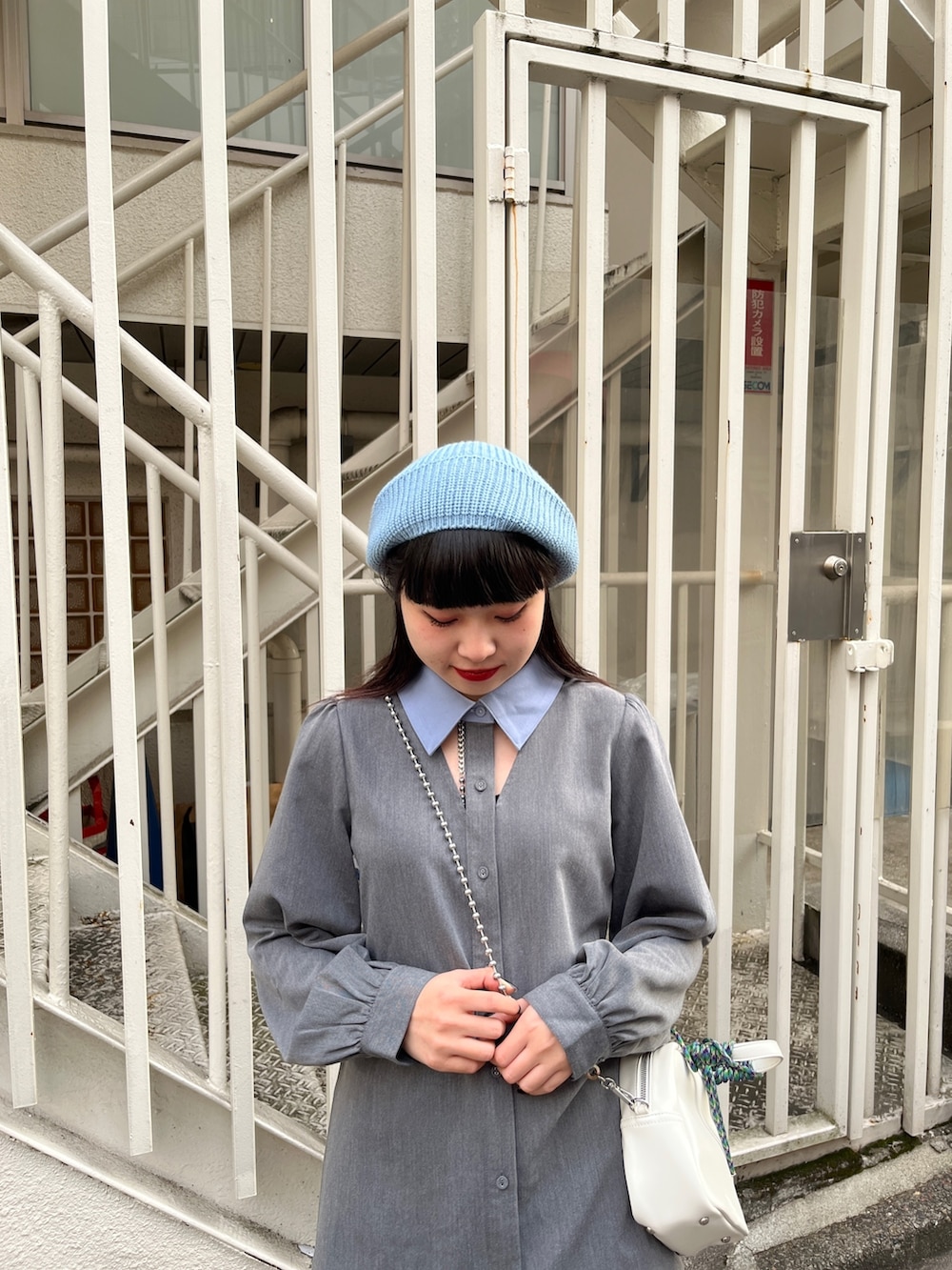 グレー系のワンピース、ブラック系のブーツ、ホワイト系のショルダーバッグを着用したレディースの冬コーディネートの4枚目の写真