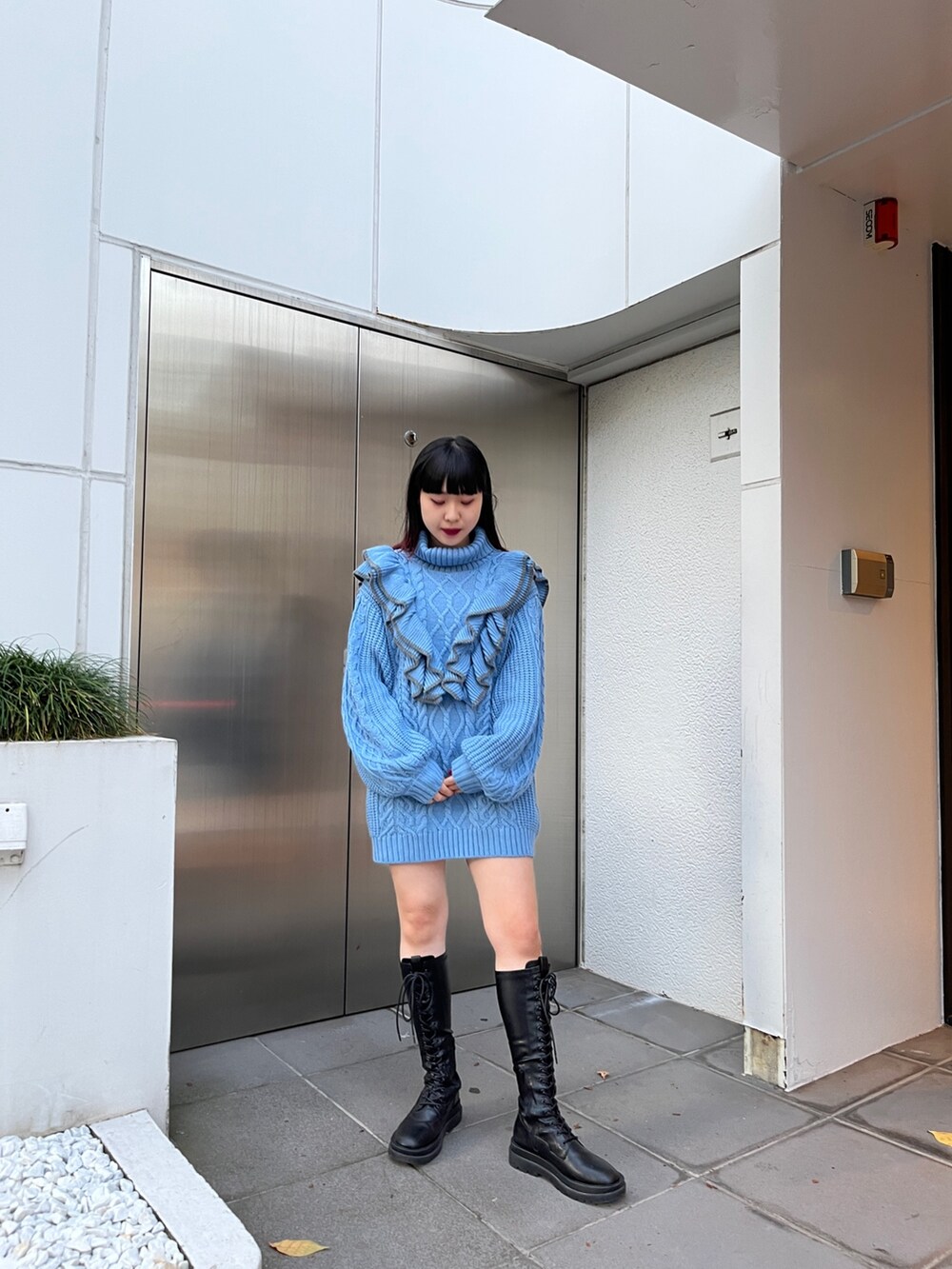 ブルー系のニット/セーター、ブラック系のブーツを着用したレディースの冬コーディネートの2枚目の写真