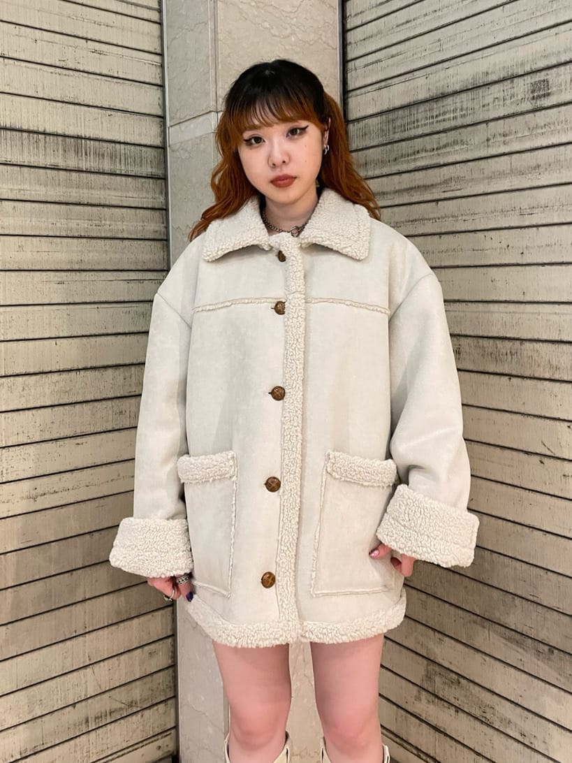 グリーン系のブーツ、ホワイト系のムートンコートを着用したレディースの夏コーディネートの3枚目の写真