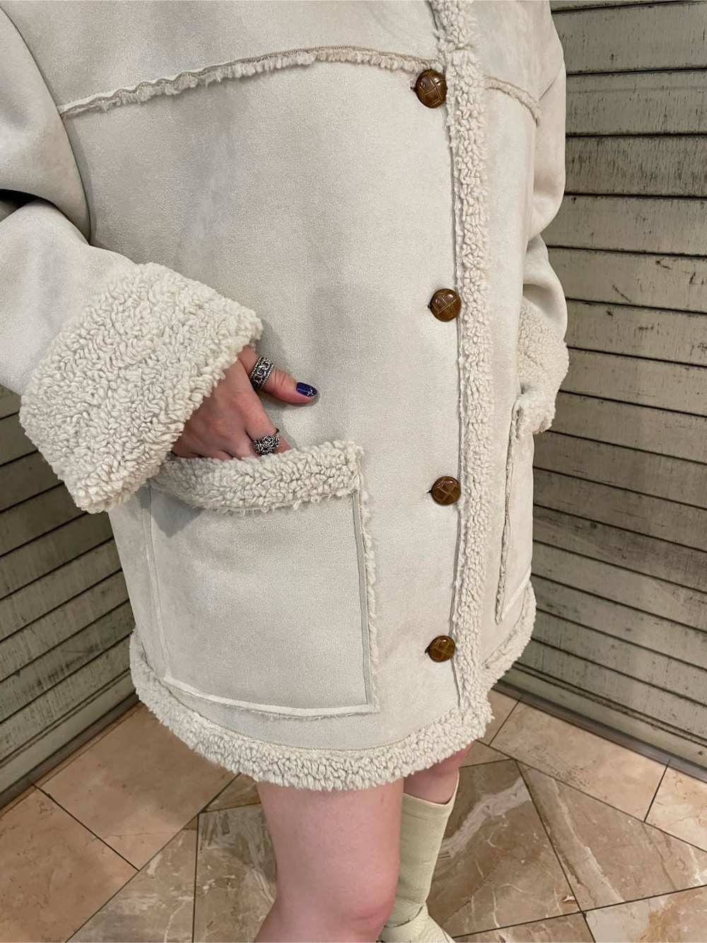 グリーン系のブーツ、ホワイト系のムートンコートを着用したレディースの夏コーディネートの5枚目の写真