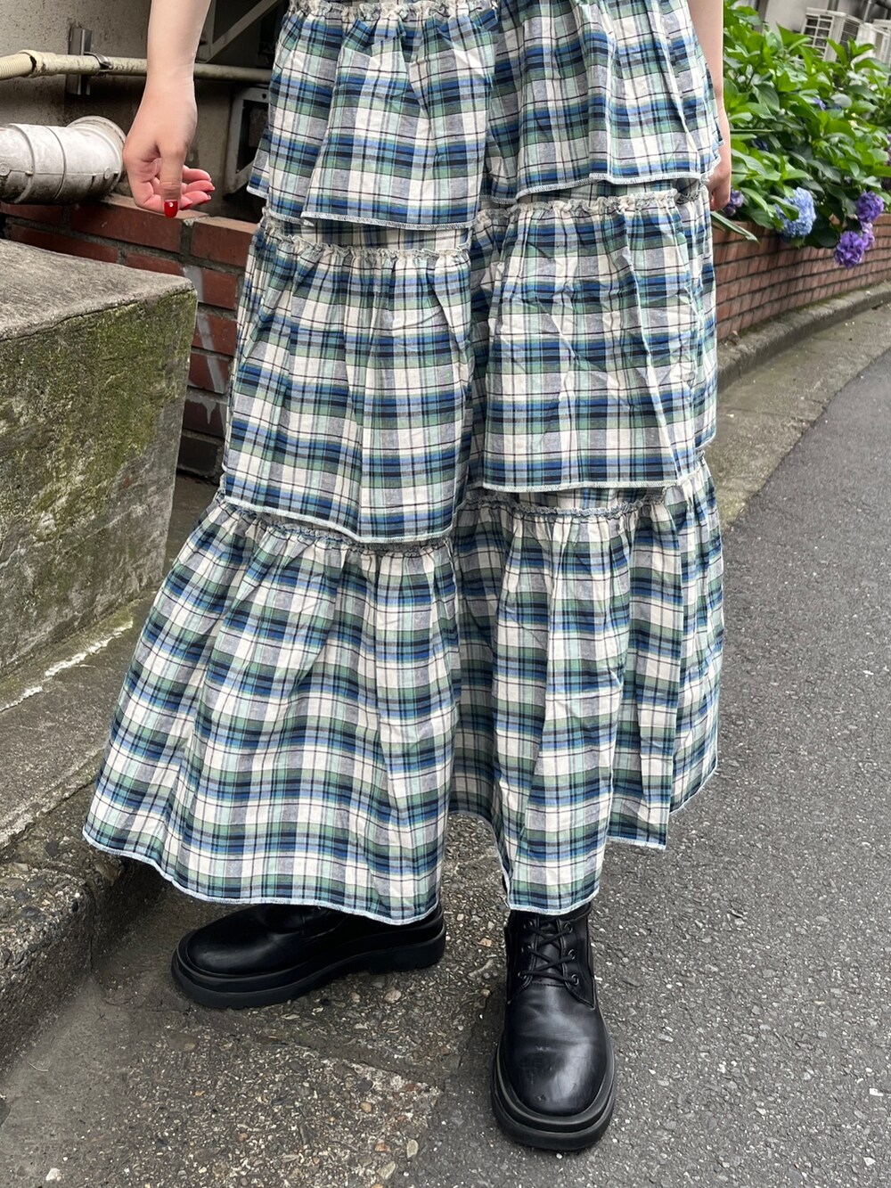 グリーン系のスカート、ブラック系のTシャツ/カットソー、ブラック系のブーツを着用したレディースの夏コーディネートの7枚目の写真