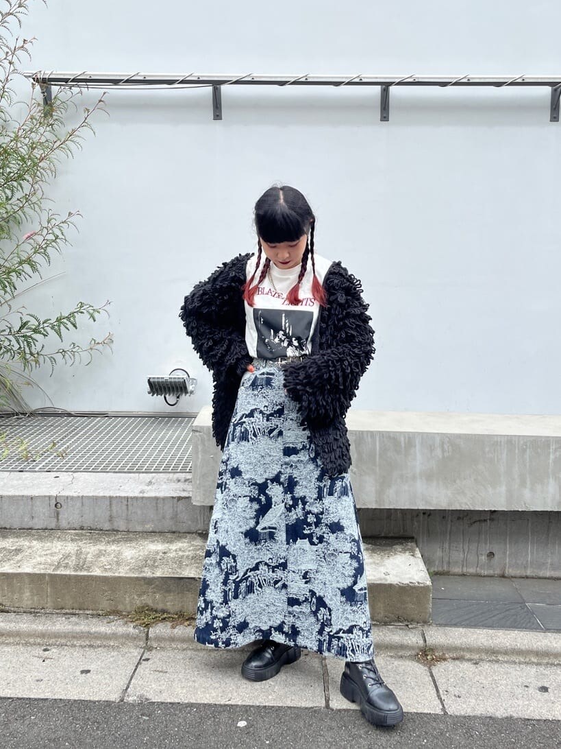 ブルー系のデニムスカート、ホワイト系のTシャツ/カットソー、ブラック系のカーディガン/ボレロを着用したレディースの秋コーディネートの2枚目の写真