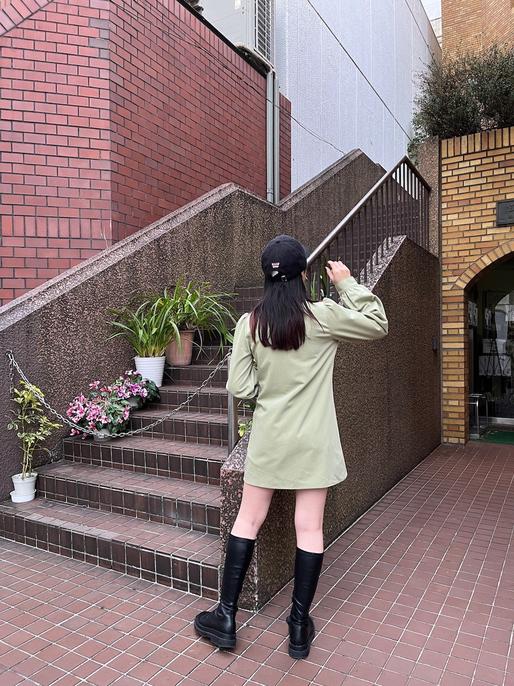 グリーン系のワンピース、ブラック系のブーツ、ブラック系のキャップを着用したレディースの冬コーディネートの4枚目の写真