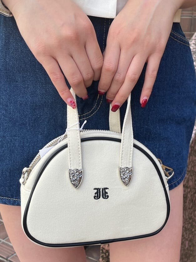 ホワイト系のボストンバッグ、ブラック系のブーツ、ブルー系のデニムスカートを着用したレディースの夏コーディネートの6枚目の写真