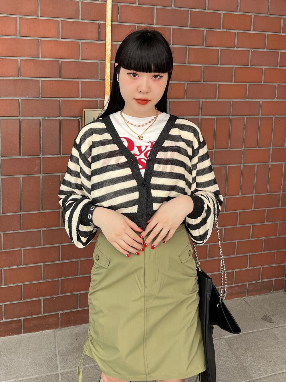 グリーン系のスカート、ブラック系のカーディガン/ボレロ、ホワイト系のTシャツ/カットソーを着用したレディースの夏コーディネートの4枚目の写真