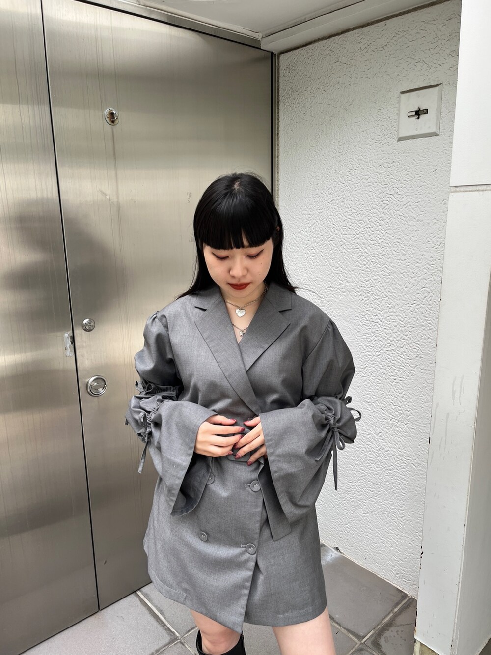 グレー系のワンピース、ブラック系のブーツ、シルバー系のネックレスを着用したレディースの夏コーディネートの5枚目の写真