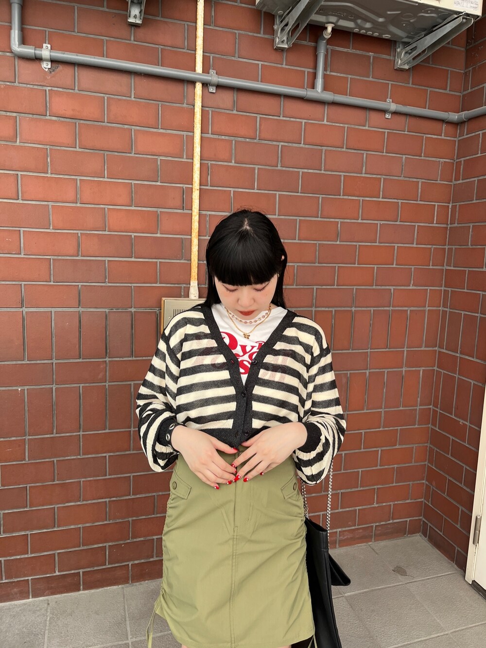 グリーン系のスカート、ブラック系のカーディガン/ボレロ、ホワイト系のTシャツ/カットソーを着用したレディースの夏コーディネートの5枚目の写真