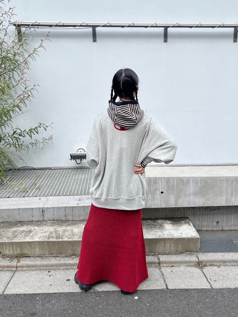 レッド系のスカート、グレー系のスウェット、ホワイト系のニットキャップ/ビーニーを着用したレディースの秋コーディネートの3枚目の写真